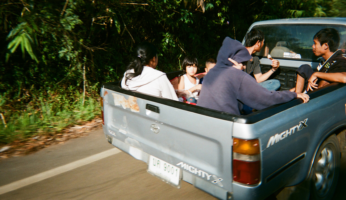 <h4><b> Mae Hong Son, Thailand <br> Fujifilm Disposable <br> November 2019 </b></h4>
					<h4> Taken from the back of my dad’s motorbike when touring Northern Thailand, I captured this photograph of a family of 6 in the bed of a truck. Many times when using point and shoots on film, you never know how the shot will really turn out. I was pleasantly surprised with this one, with the expression of the little boy and the motion blur of an overtaking-motorcyclist on a bendy road. </h4>